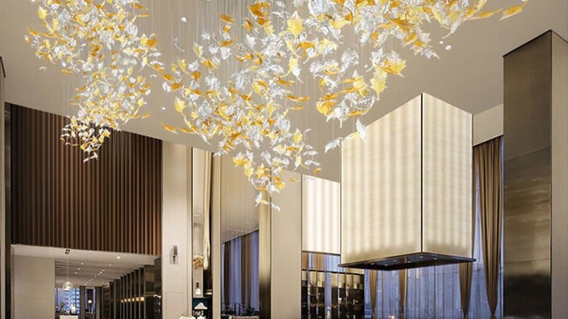 A bespoke glass leaf installation suspended across a double-height lobby ceiling