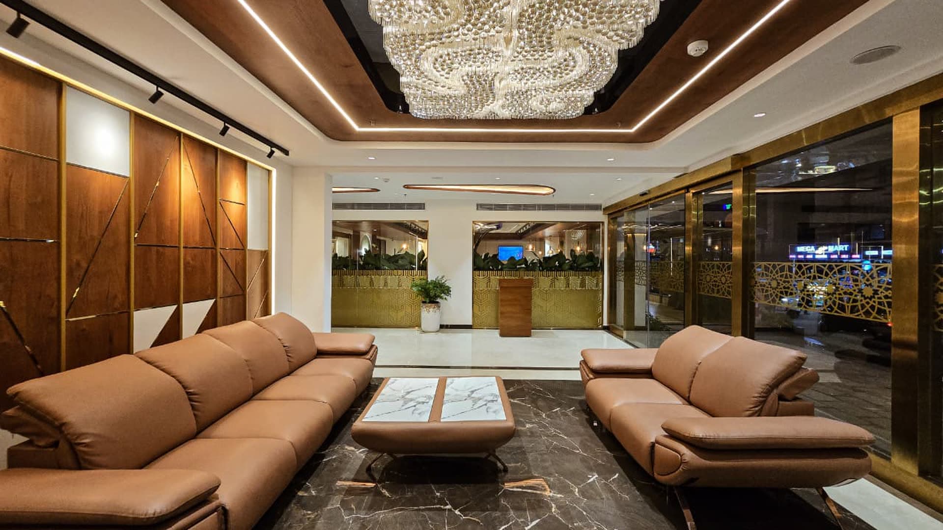 A hotel lobby lit by a wide crystal ceiling installation over lounge seating