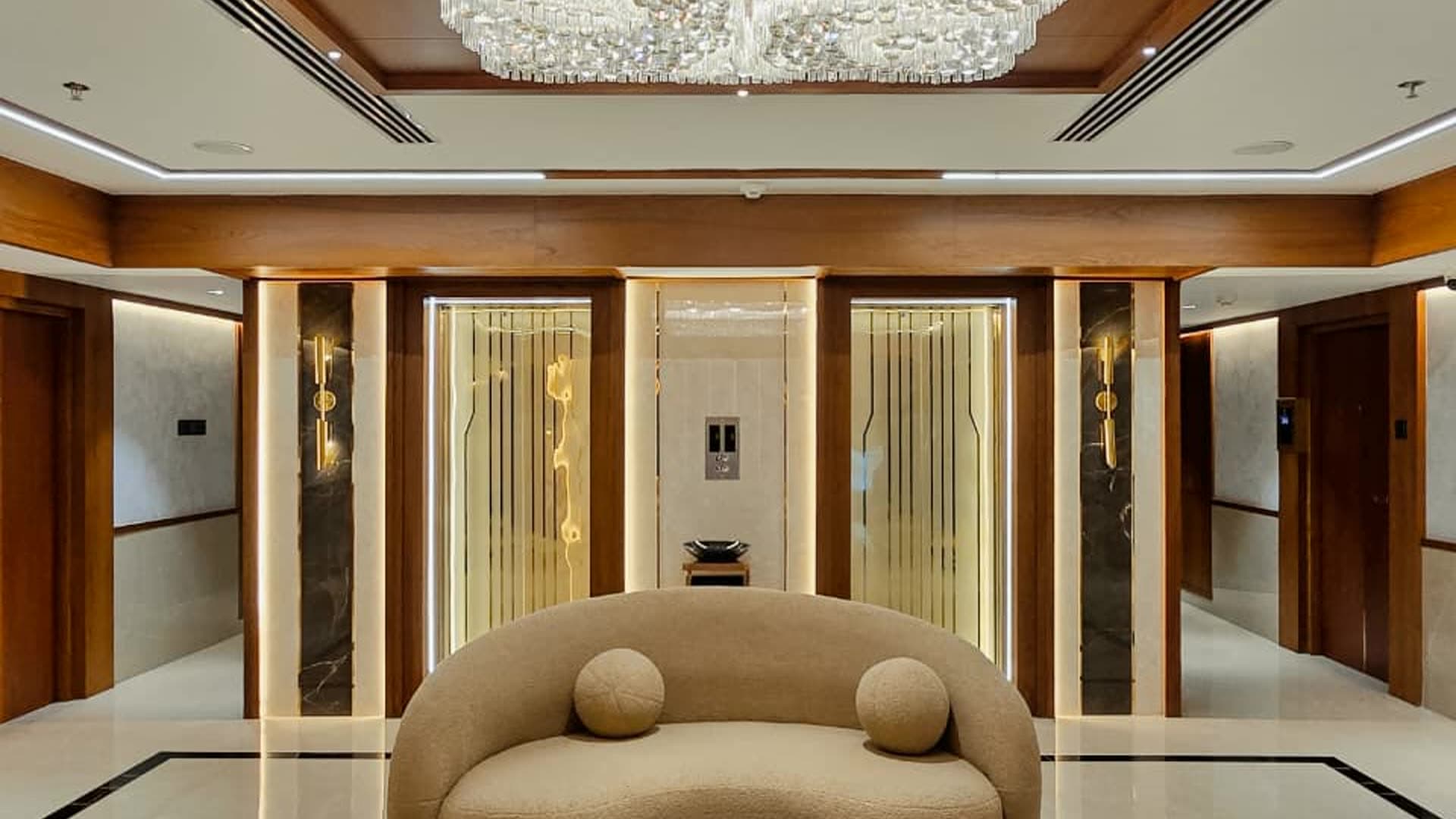 A finished lounge lit end to end, a crystal ceiling fixture over warm layered lighting