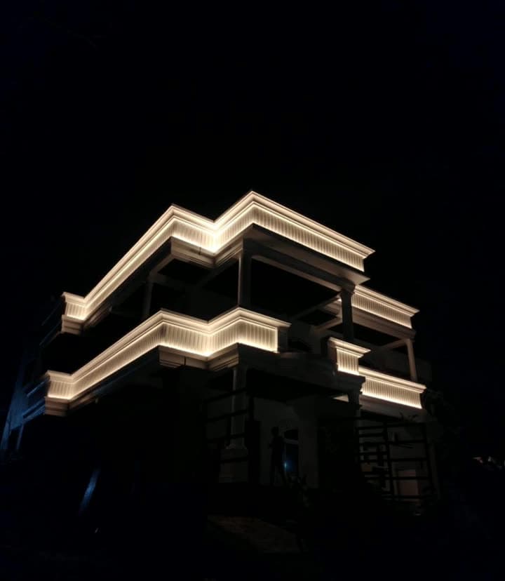 A building facade at night with its terraces outlined in warm cove lighting